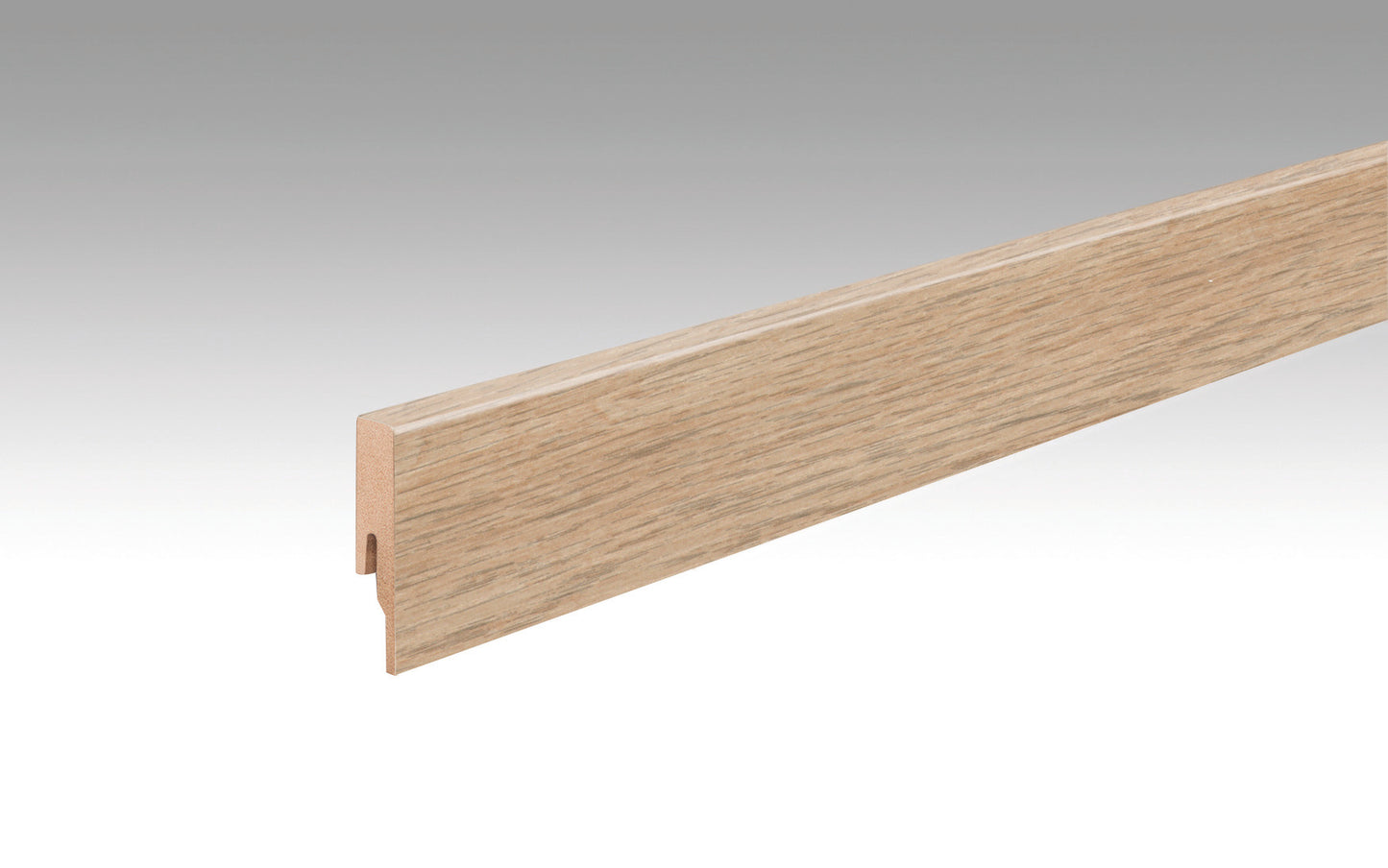 Eine lange, rechtwinklige Fußleiste aus Holz mit hellbrauner Fjordeicheoptik, glatte Oberfläche, Maserung sichtbar.