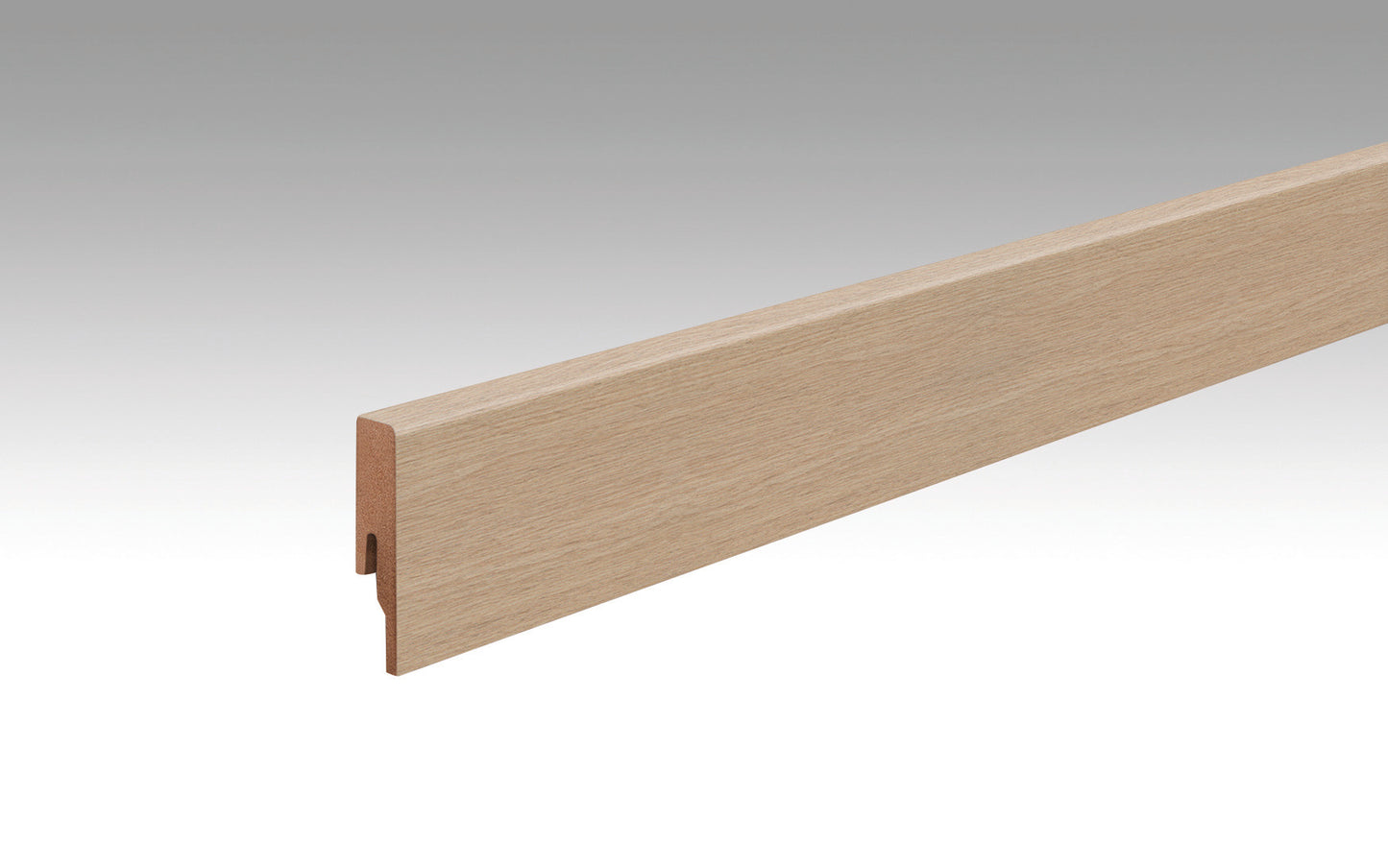 Eine längliche, gerade Fußleiste aus Holz mit heller, eichenähnlicher Maserung. Klare Kanten, Profilquerschnitt sichtbar.