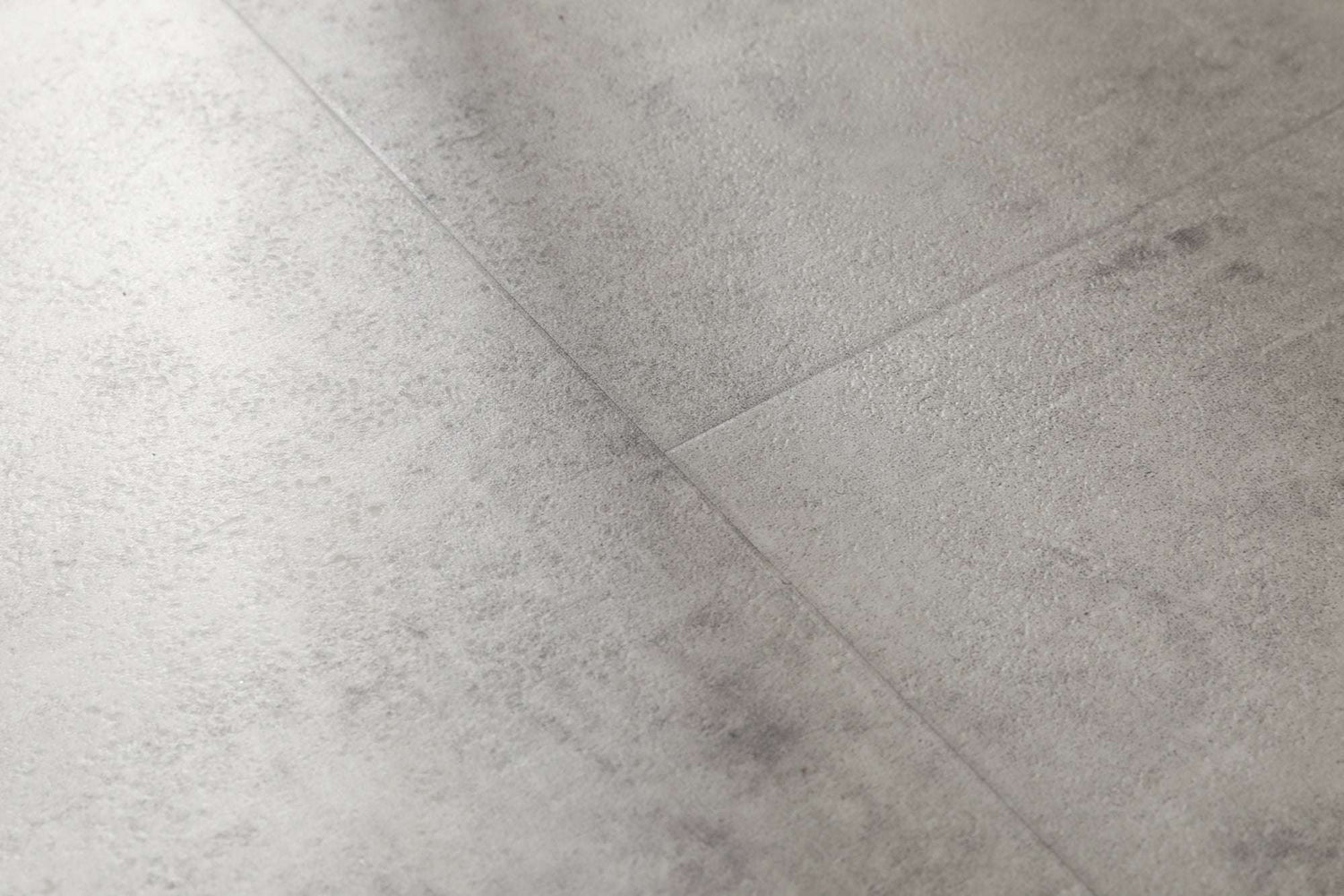 Mehrere graue Fliesen mit leicht strukturierter, rauer Oberfläche und feinen Fugen verlaufen schräg durch das Bild.