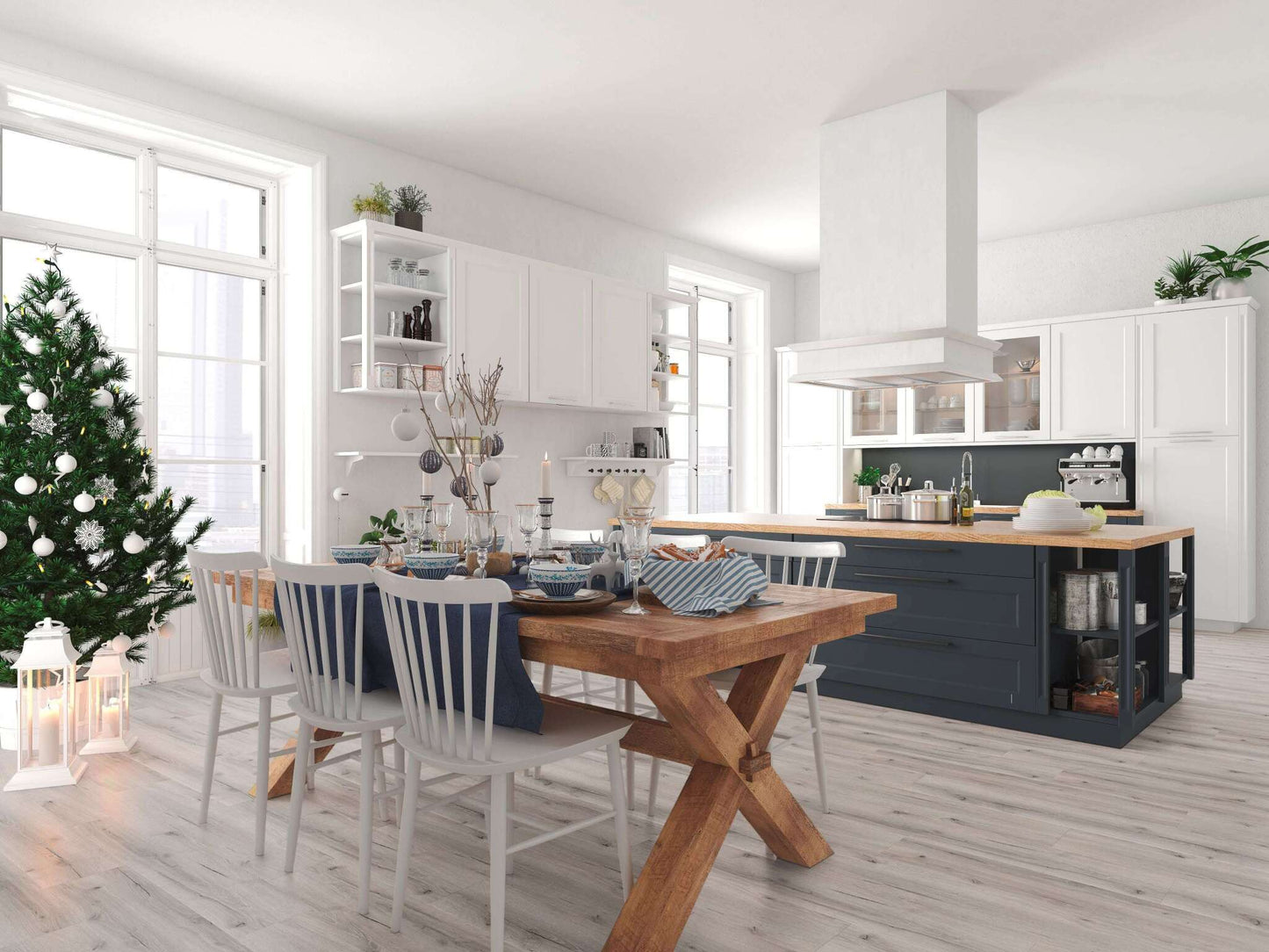 Heller Küchenraum mit großem Holz-Esstisch, sechs weißen Stühlen, festlicher gedeckter Tafel, geschmücktem Weihnachtsbaum, Kücheninsel, weißen Schränken, Pflanzen und Dekorationen.