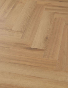 Mehrere Holzdielen mit hellbrauner Holzmaserung sind im Fischgrätmuster verlegt, Oberfläche glatt und gepflegt.