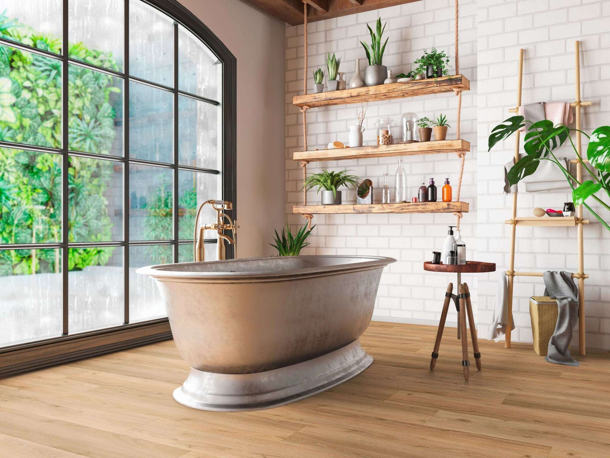 Freistehende Badewanne mit goldener Armatur vor großem Fenster, Holzboden, Wandregale mit Pflanzen, Handtüchern und Flaschen
