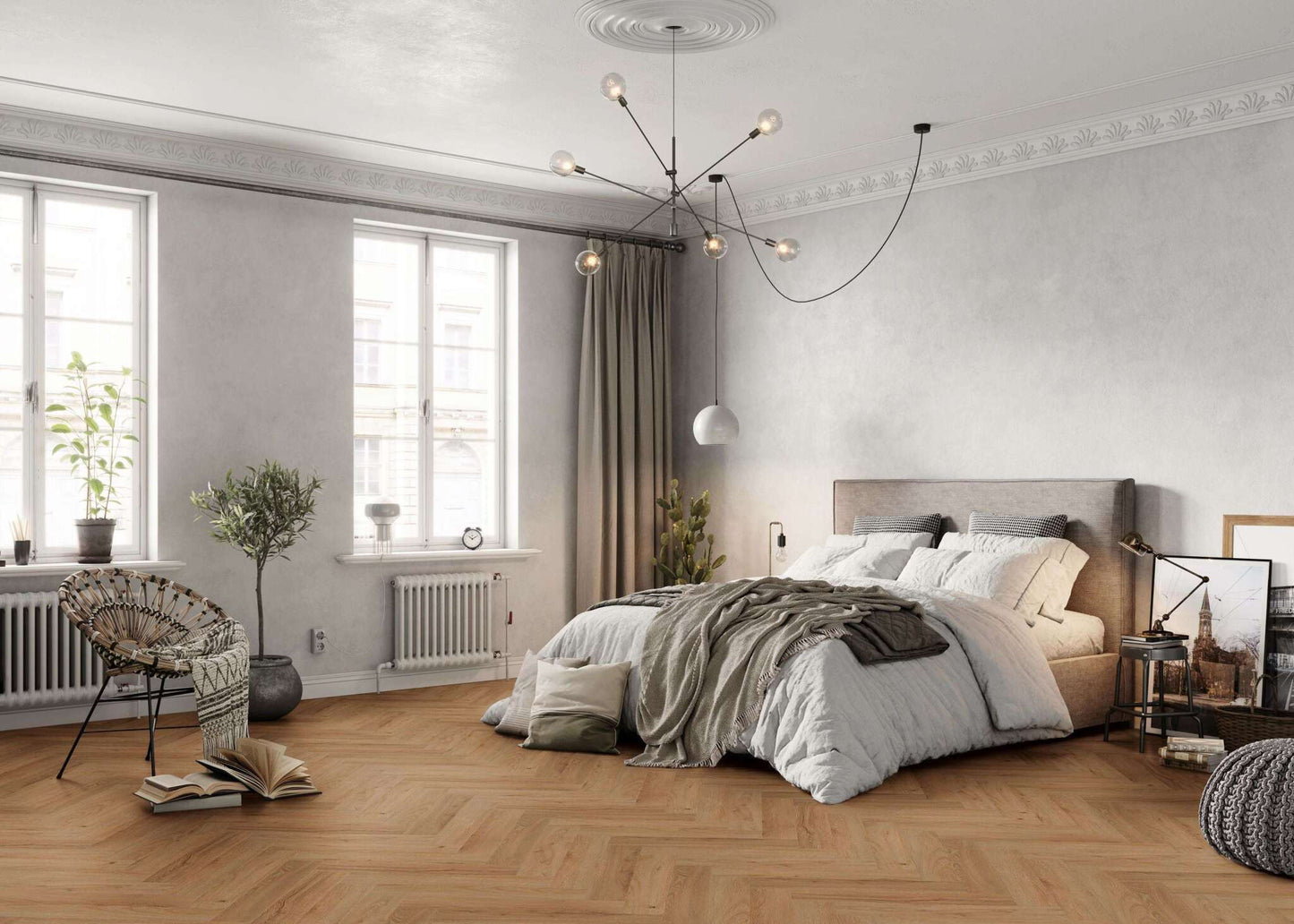 Modernes Schlafzimmer mit großem Bett, grauem Kopfteil, vielen Kissen und Decken, hölzernem Boden, Sessel, Grünpflanzen, geöffnetem Buch, zwei großen Fenstern, Vorhängen, moderner Deckenlampe, Nachttisch, Stehlampe, Bildern an der Wand, beigem Sitzpouf und Heizkörper.