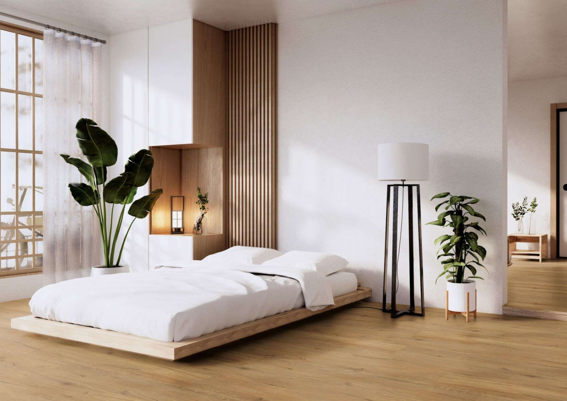 Modernes Schlafzimmer mit niedrigem Holzbett, weißer Bettwäsche, großer Zimmerpflanze, Stehlampe, Holzfußboden, Tageslicht und minimalistischer Deko.